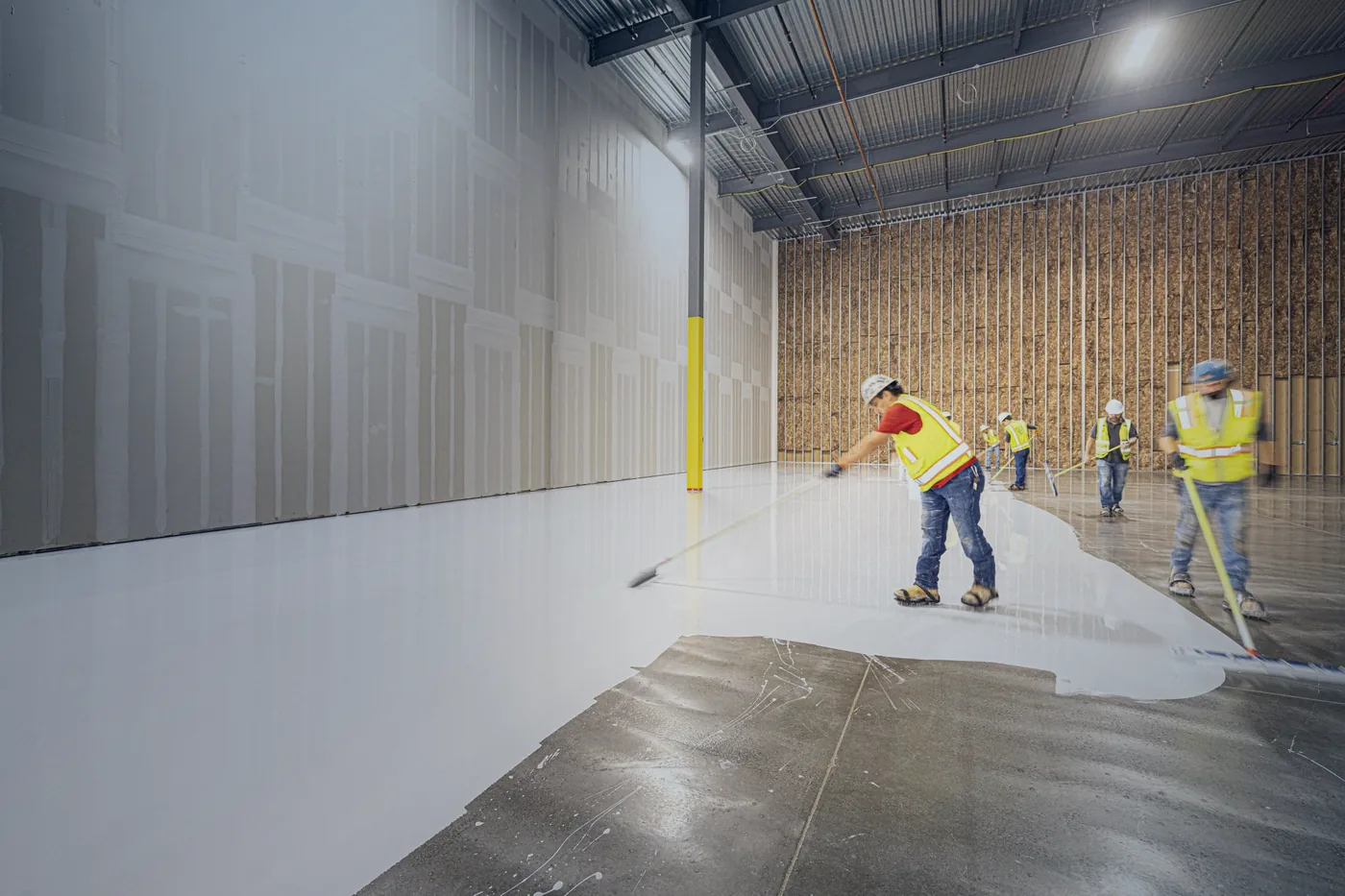 A crew levelling a large interior floor screed